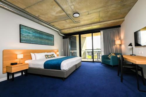 Nesuto Curtin Perth Hotel في بيرث: غرفة في الفندق بها سرير ومكتب ومكتب