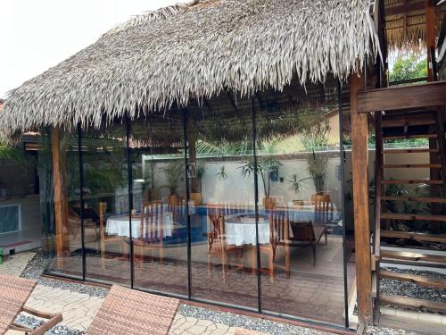 a restaurant with a thatched roof with tables and chairs at Villa Éden in Alter do Chao