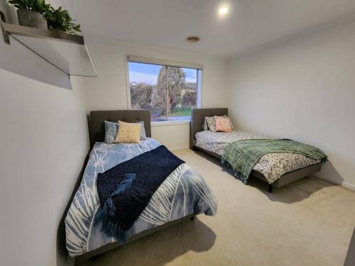 two beds in a room with a window at Centelle Park Farm Stay in Kilmore East