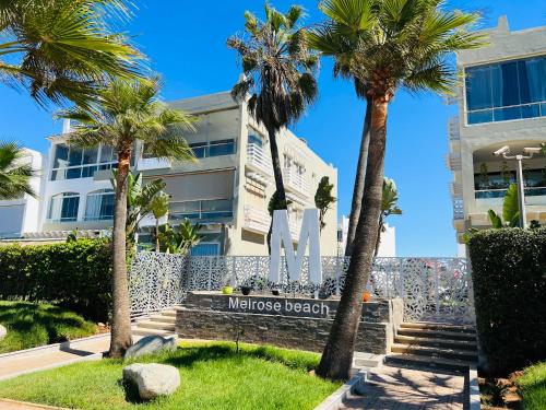 a sign in front of a building with palm trees at Melrose Beαch Aρραrt Pοοl Vieω in Casablanca