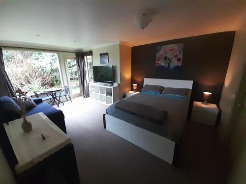 a bedroom with a bed and a living room at Georges BnB Nature and Lifestyle Retreat in New Plymouth