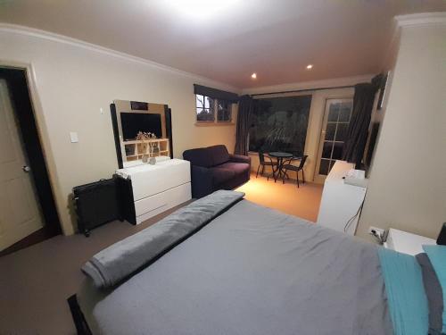 a bedroom with a bed and a living room at Georges BnB Nature and Lifestyle Retreat in New Plymouth