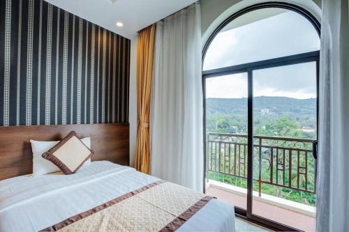 a bedroom with a bed and a large window at Nesta Hotel Phu Quoc in Phu Quoc