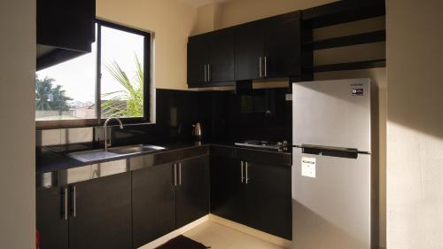 a kitchen with black cabinets and a refrigerator at Garden Vista Hotel in Davao City
