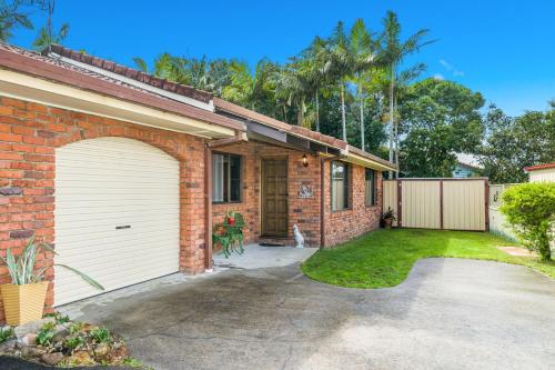 a brick house with a garage and a driveway at Bromeliads in Iluka