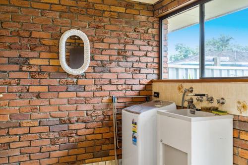 baño con pared de ladrillo y lavamanos en Bromeliads, en Iluka