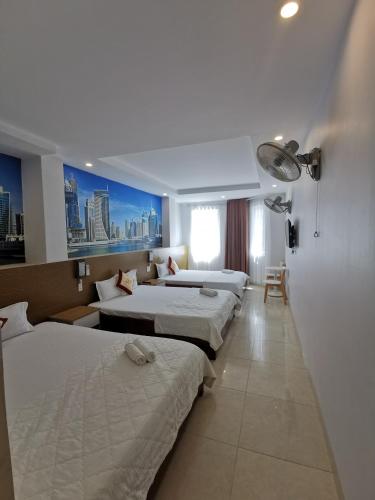 a hotel room with three beds and a window at Sen Vàng Hotel in Xã Thang Tam