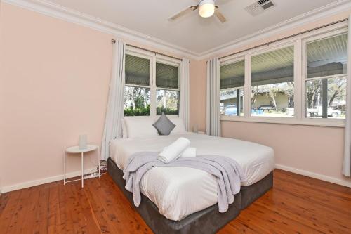 a bedroom with a large white bed with windows at Glandore Estate Homestead in Pokolbin