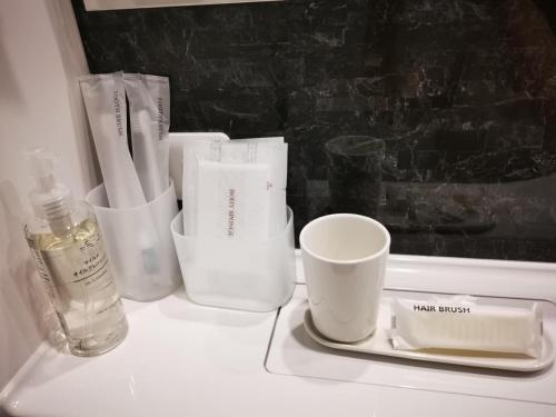 Un mostrador blanco con tazas y una botella. en Leisure hotel 中野, en Tokio