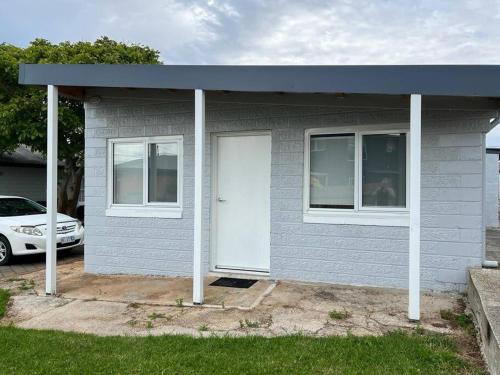 a small house with a white door and a car at Modern 1 bedroom studio free parking close to CBD in Burnie