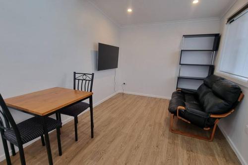 sala de estar con mesa, silla y sofá en Modern 1 bedroom studio free parking close to CBD, en Burnie