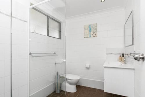 a white bathroom with a toilet and a sink at Iluka Villa 10 in Iluka