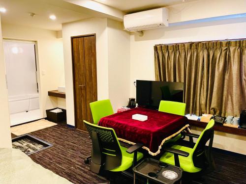 a room with a table with green chairs and a desk at AYA Hotel in Tokyo