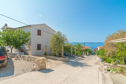 a street with a house and the ocean in the background at Apartments by the sea Zdrelac, Pasman - 15911 in Ždrelac