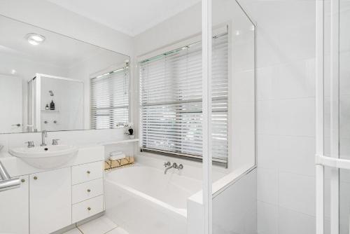 ein weißes Badezimmer mit einer Badewanne und einem Waschbecken in der Unterkunft Villa di Luka in Iluka