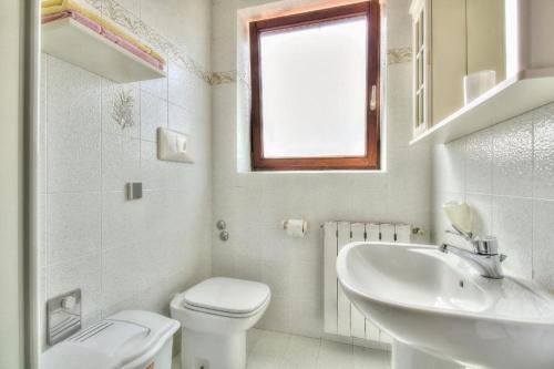 biała łazienka z toaletą i umywalką w obiekcie Apartments with a parking space Umag - 15941 w mieście Umag