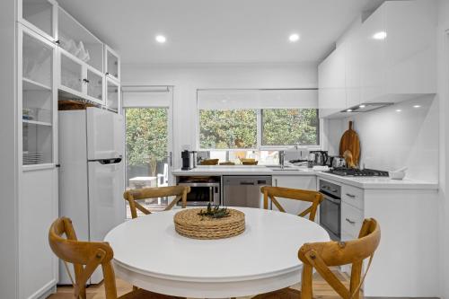 a white kitchen with a white table and chairs at Capella Villa No. 3 - Luxurious beachside style in Blairgowrie