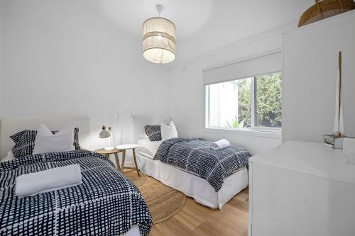 - une chambre blanche avec 2 lits et un canapé dans l'établissement Capella Villa No. 3 - Luxurious beachside style, à Blairgowrie
