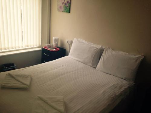 Schlafzimmer mit einem Bett mit weißer Bettwäsche und Kissen in der Unterkunft Peek-a-Booze - Budget Hotel - Adults Only in Blackpool