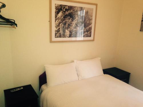 ein Schlafzimmer mit einem Bett und einem Bild an der Wand in der Unterkunft Peek-a-Booze - Budget Hotel - Adults Only in Blackpool