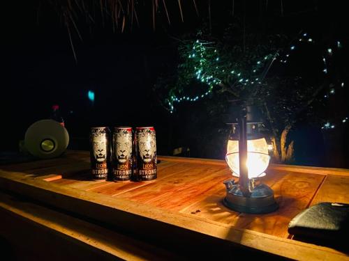 einen Tisch mit einer beleuchteten Kerze und drei Dosen darauf in der Unterkunft The Cliff Tea Glamping in Badulla