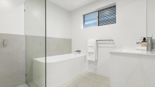 a white bathroom with a tub and a sink at Coastal House in Gold Coast