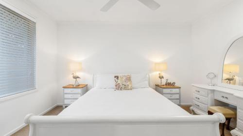 a white bedroom with a bed and a mirror at Coastal House in Gold Coast