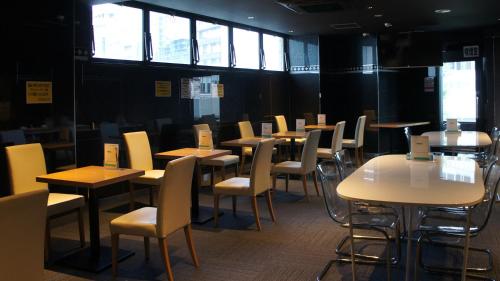 un comedor con mesas, sillas y ventanas en Men Only Capsule Room & Sauna, Bathhouse 男性専用サウナ&カプセル Minami Roppongi, en Tokio
