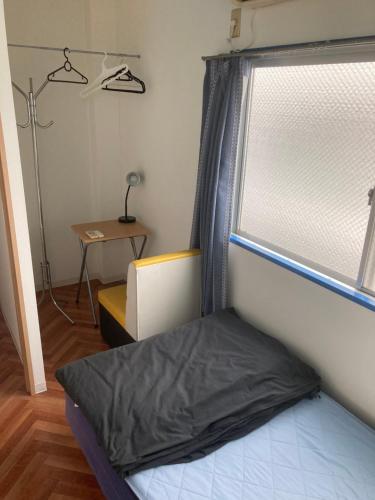 a small bedroom with a bed and a window at Music Uni Street Backpacker's Hostel in Toyonaka