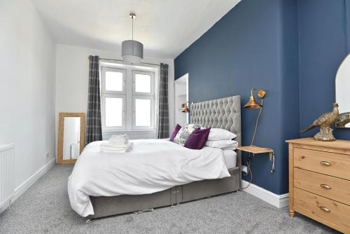 a bedroom with a large bed and a blue wall at The John Muir - Beautiful 1 bed apartment in Helensburgh in Helensburgh