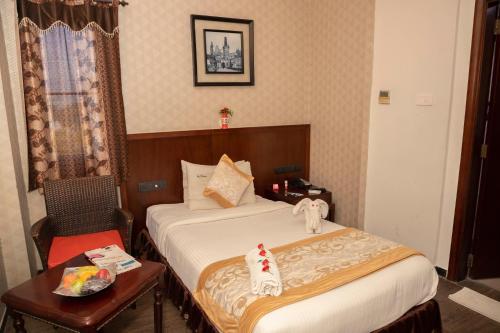 a hotel room with a bed and a table with a chair at THE PEBBLE Boutique Hotel in Tiruppūr