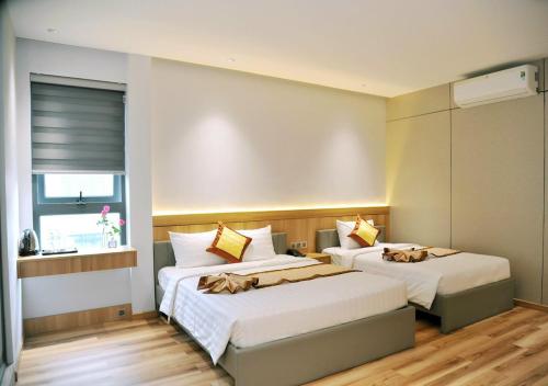 a bedroom with two beds and a window at Khách Sạn LUCIEN HOTEL Quy Nhơn in Quy Nhon