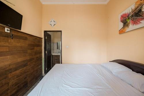 a bedroom with a bed and a flat screen tv at Pelangi Homestay Bedugul RedPartner in Bedugul