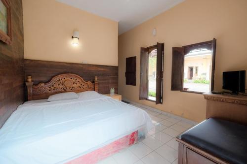 a bedroom with a large white bed and a television at Pelangi Homestay Bedugul RedPartner in Bedugul