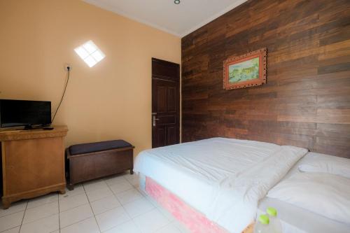 a bedroom with a bed with a wooden wall at Pelangi Homestay Bedugul RedPartner in Bedugul