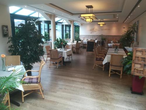 un comedor con mesas, sillas y plantas en Hotel Zum Märchenwald, en Lingen