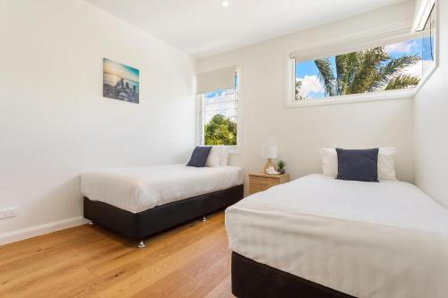 2 camas en una habitación con 2 ventanas en Ocean Sapphire, en Byron Bay