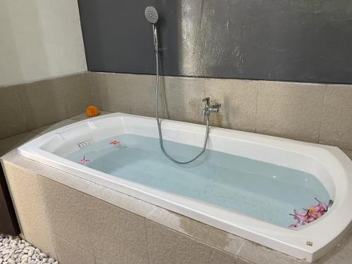 a bath tub with a shower in it at The Palms Canggu in Canggu