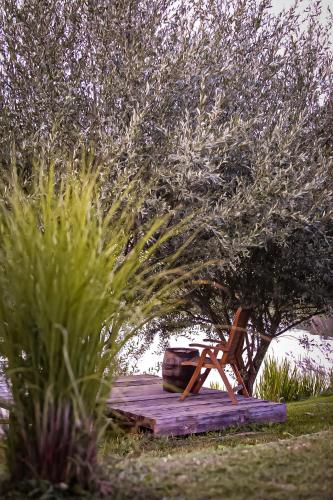 a wooden deck with a chair under a tree at House Arupium - HOT TUB in Otočac