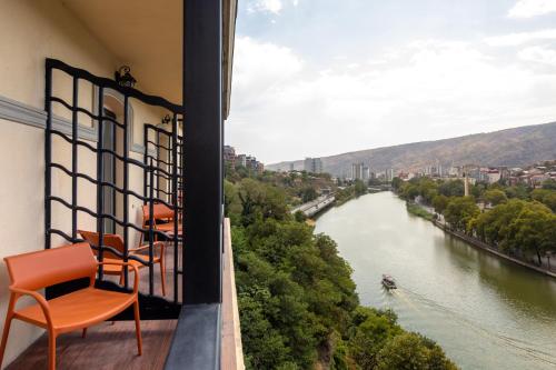 a balcony with chairs and a view of a river at Margot Old Tbilisi in Tbilisi City