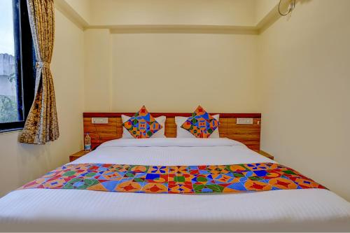 een slaapkamer met een bed met een kleurrijke quilt bij FabHotel Crystal Homes in Pune