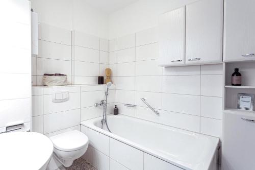 e bagno bianco con servizi igienici e vasca. di Cozy 4 room apartment in Hilden a Hilden