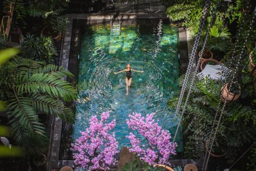 a woman is swimming in a pool in a garden at Manon Les Suites Guldsmeden in Copenhagen
