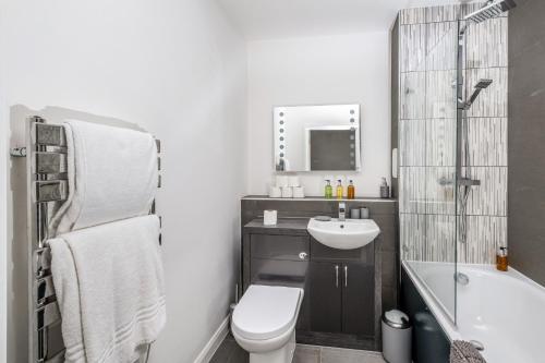 a bathroom with a sink and a toilet and a bath tub at Town Center 2 bed Serviced Apartment 08 with parking, Surbiton By 360Stays in Surbiton