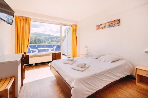 a bedroom with a large bed and a large window at Village Vacances Le Mongade (by Popinns) in Plainfaing