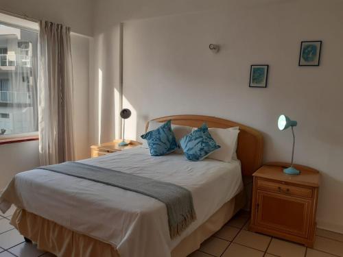 ein Schlafzimmer mit einem Bett mit blauen Kissen und einem Fenster in der Unterkunft Seabrook 306 in Margate