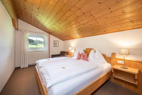 a bedroom with a large white bed with a wooden ceiling at Aparthotel Stadler in Flachau