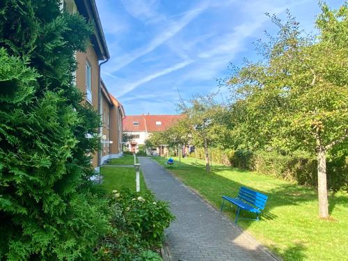 eine blaue Bank auf einem Bürgersteig neben einem Gebäude in der Unterkunft Apartment Casa Heideweg mit TG direkt an der Heide in Dresden