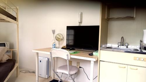 uma cozinha com uma secretária, uma televisão e uma cadeira em Guest house Shijo K12 A202 em Quioto