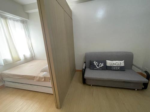 - une petite chambre avec un lit et un miroir dans l'établissement Trees Residences Fairview, à Manille